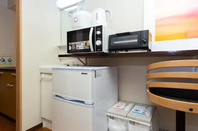 a small kitchen with a white refrigerator and a microwave at \u5510\u6ca2\u30db\u30c6\u30eb Karasawa-Hotel in Tokyo