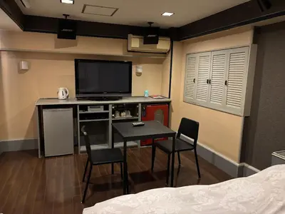 a room with a tv and a table and chairs at City Hotel Dolphin in Tokyo