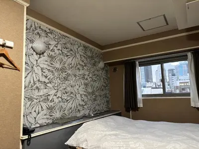 a bedroom with a wall with a floral wallpaper at City Hotel Dolphin in Tokyo