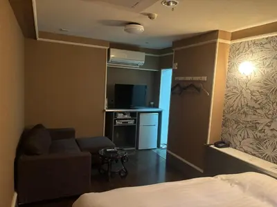 a room with a bed and a couch and a tv at City Hotel Dolphin in Tokyo