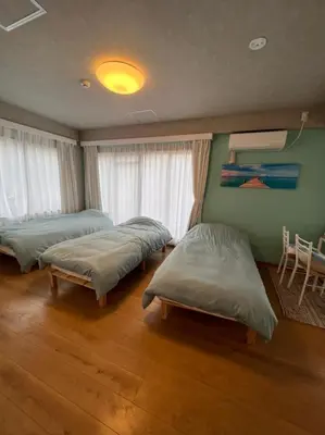 a bedroom with two beds and a table and windows at Upper Hotel Ishihara in Tokyo