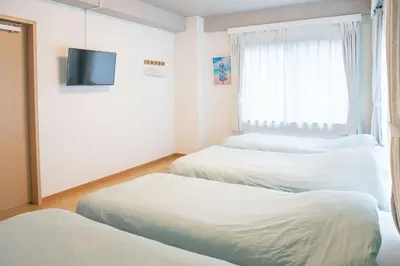 a room with two beds and a tv and a window at Upper Hotel Ishihara in Tokyo
