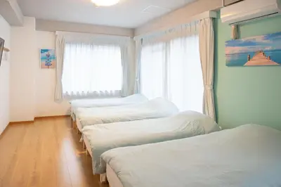 a room with three beds and a window at Upper Hotel Ishihara in Tokyo