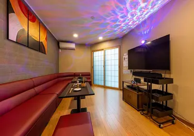 a living room with a red couch and a flat screen tv at YADOYA Yumeji in Tokyo