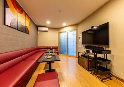 a living room with a red couch and a flat screen tv at YADOYA Yumeji in Tokyo