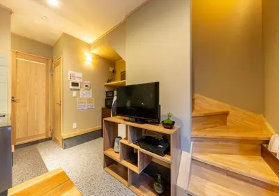 a living room with a flat screen tv and wooden stairs at YADOYA Iroha in Tokyo