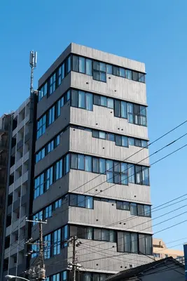 a tall gray building with glass windows at PRISM INN OGU in Tokyo