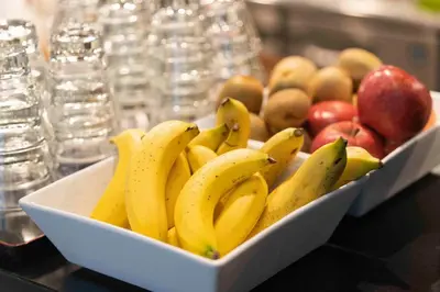 a bowl of bananas and apples on a table at Courtyard by Marriott Tokyo Station in Tokyo