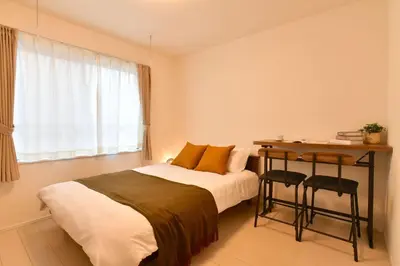 a bedroom with a bed and a desk and a window at FL Residence Todai II in Tokyo