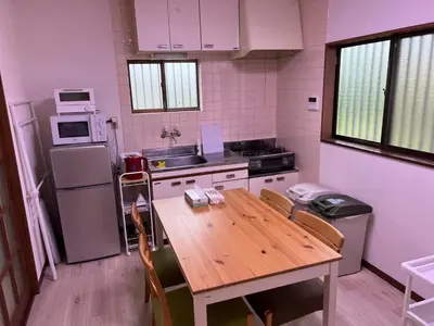 a kitchen with a wooden table and a refrigerator at Sepia Court Inn \u30bb\u30d4\u30a2\u30b3\u30fc\u30c8\u30a4\u30f3 in Urayasu