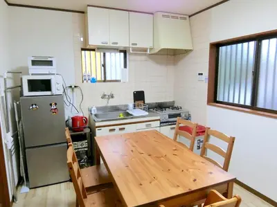 a kitchen with a wooden table and a refrigerator at Sepia Court Inn \u30bb\u30d4\u30a2\u30b3\u30fc\u30c8\u30a4\u30f3 in Urayasu