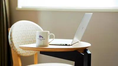 a laptop computer sitting on a table with a coffee mug at Hotel Monte Hermana Tokyo in Tokyo