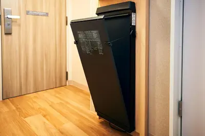 a black refrigerator sitting in a hallway next to a door at Hotel Monte Hermana Tokyo in Tokyo