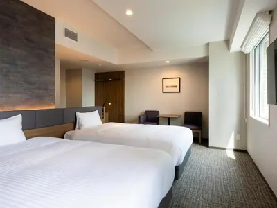 a hotel room with two beds and a table at Hotel Rilassare Tokyo in Tokyo