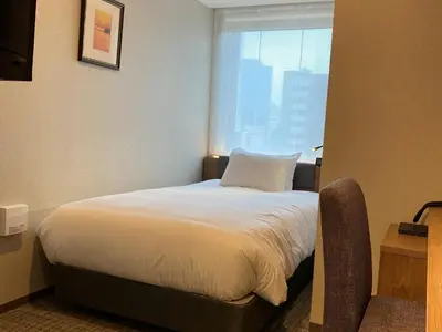 a bed in a hotel room with a window at Hotel Rilassare Tokyo in Tokyo