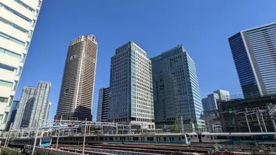 a train in front of a city with tall buildings at Hotel Rilassare Tokyo in Tokyo
