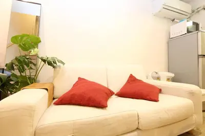 a white couch with two red pillows on it at Takemura Building106 in Tokyo