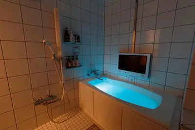 a bathroom with a tub with a tv on the wall at HOTEL555 \u9326\u7cf8\u753a in Tokyo