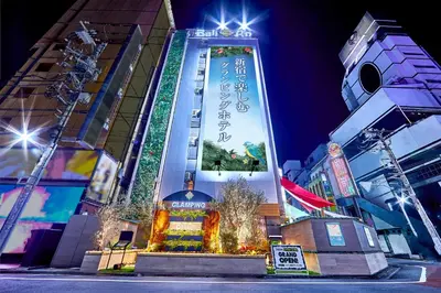 a tall building with a sign on it at night at Hotel BaliAn Resort Shinjuku Glamping in Tokyo
