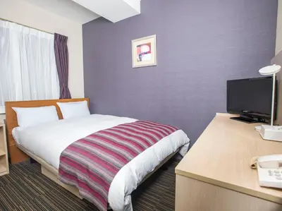 a hotel room with a bed and a desk with a television at FLEXSTAY INN Shinagawa in Tokyo