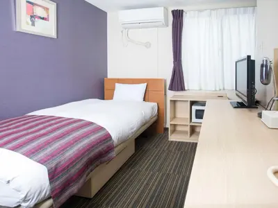 a hotel room with a bed and a flat screen tv at FLEXSTAY INN Shinagawa in Tokyo