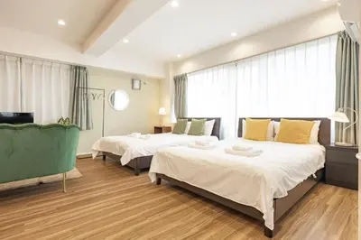 a hotel room with two beds and a chair at Hotel Estasia Ryogoku in Tokyo