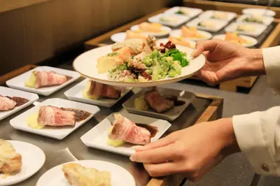 a person holding a plate of food on a table at Via Inn Prime Akasaka in Tokyo