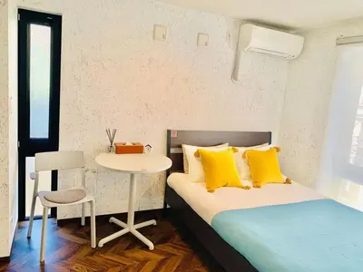 a bedroom with a bed with yellow pillows and a table at TIME SHARING STAY Ikebukuro in Tokyo