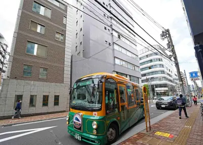 a green and orange bus on a city street at Ryoma THE TOWER - Vacation STAY 12892 in Tokyo