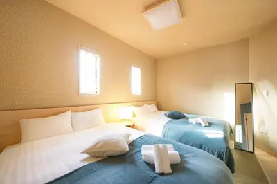 a room with two beds with a cross on the bed at Ciel-home in Tokyo
