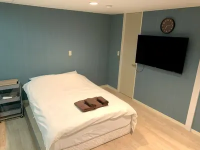 a bedroom with a bed with a tv on the wall at \u30b0\u30e9\u30f3\u30c7\u30a3\u30aa\u30fc\u30bd\u4e2d\u91ce\u5bcc\u58eb\u898b\u753a in Tokyo
