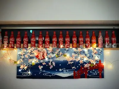 a display of coca cola bottles on a wall at K.House in Tokyo