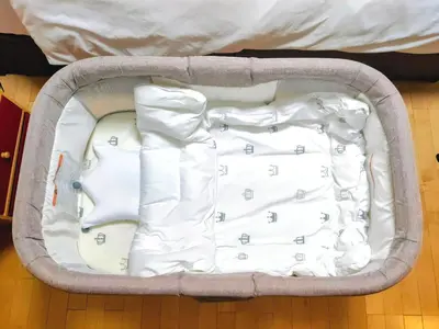 a baby sleeping in a suitcase on the floor at K.House in Tokyo
