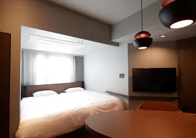 a bedroom with a bed and a tv and a table at COCOSHUKU AKASAKA Premium in Tokyo