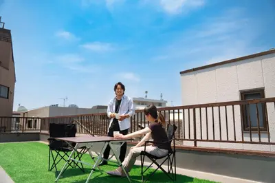 a man and woman sitting at a table on a balcony at \u5317\u65b0\u5bbf\u30a6\u30c3\u30c9\u30a6\u30a9\u30fc\u30eb\u30b9\u30c6\u30a4 in Tokyo
