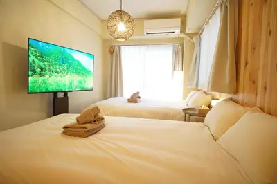 a bedroom with two beds and a flat screen tv at \u5317\u65b0\u5bbf\u30a6\u30c3\u30c9\u30a6\u30a9\u30fc\u30eb\u30b9\u30c6\u30a4 in Tokyo