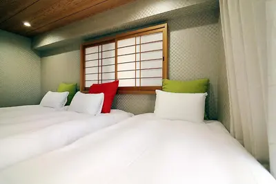 two twin beds in a room with a window at KANDA HOUSE!! Shin-Okubo Walkable Modern Stay with Shinjuku Access in Tokyo