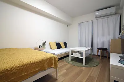 a white bedroom with a bed and a table at GM Shinjuku in Tokyo