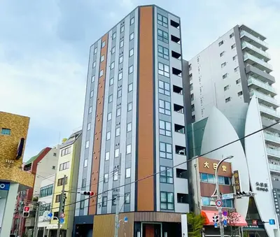 a tall building on a city street with buildings at KOKO HOTEL Residence Asakusa Tawaramachi in Tokyo