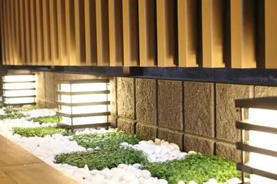 a garden with rocks and grass next to a wall at KOKO HOTEL Residence Asakusa Tawaramachi in Tokyo