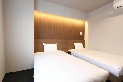 two beds in a room with white sheets at KOKO HOTEL Residence Asakusa Tawaramachi in Tokyo