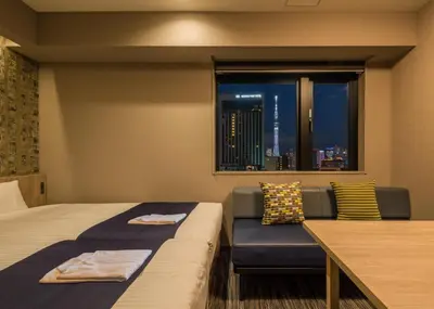 a hotel room with a bed and a couch and a window at KOKO HOTEL Residence Asakusa Kappabashi in Tokyo