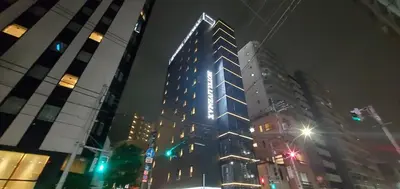 a tall building with lights on it at night at HOTEL LiVEMAX Kamata Ekimae in Tokyo