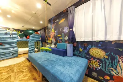 a childrens room with a blue couch and a mural at Holy Town in Tokyo