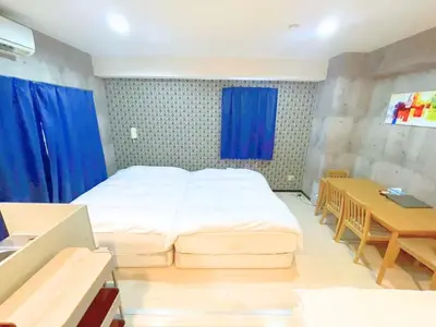 a bedroom with a bed and a table and blue curtains at Green House Nakano Fujimicho - Vacation STAY 65976v in Tokyo