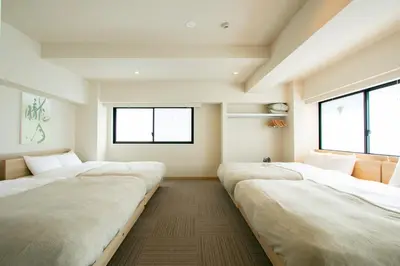 a row of beds in a room with windows at Ostay Ueno in Tokyo