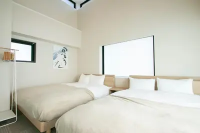 two beds in a white room with a window at Ostay Ueno in Tokyo