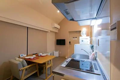 a small kitchen with a table and a refrigerator at Ostay Ueno in Tokyo