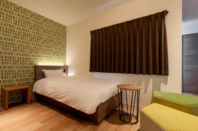 a bedroom with a bed and a chair and a window at COCOSHUKU Asakusa Kuramae in Tokyo