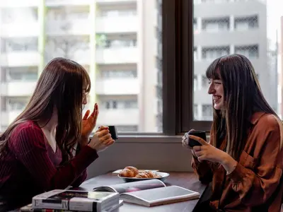 two women sitting at a table looking at their cell phones at COCOSHUKU Shinjuku-Hanazono in Tokyo